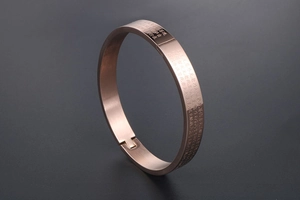 Detailed macro view of rose gold stainless steel bangle with engraved heart sutra text