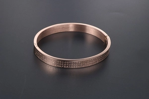 Detail of rose gold heart sutra bangle with brushed finish and side clasp closure