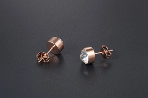 Detail of a rose gold titanium steel stud earring featuring a large faceted clear zircon