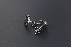 Macro detail of gothic titanium steel cross earrings with black enamel and butterfly clasp