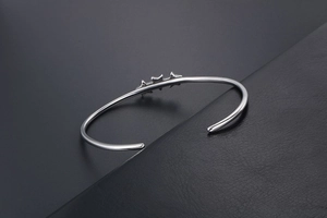 Gros plan détaillé sur un bracelet jonc en acier inoxydable argenté avec étoiles