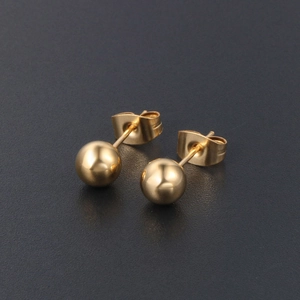 Boucles d'oreilles boules en titane doré poli avec fermoirs papillon sur fond sombre