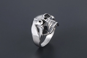 Macro shot of silver titanium steel skull ring showing detailed punk gothic texture