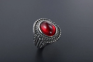 Macro shot of vintage titanium steel ring with an oval red gemstone and embossed patterns