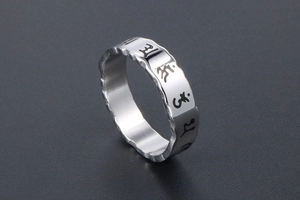 Macro view of wave-edged silver steel ring with Buddhist mantra symbols and polished finish