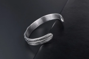 Detailed close-up of retro feather patterned silver steel cuff bracelet with vintage finish