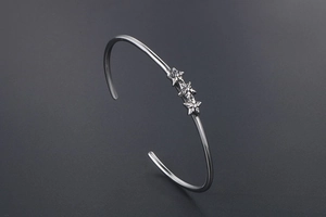 Vue macro d'un bracelet en acier argenté en C avec trois étoiles et style punk