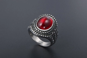 Macro side view of vintage men's steel ring with a large oval red gemstone and carvings