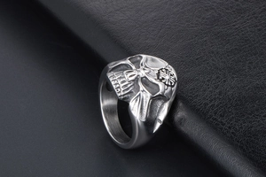 Macro shot of detailed skull carving on stainless steel ring over black leather texture