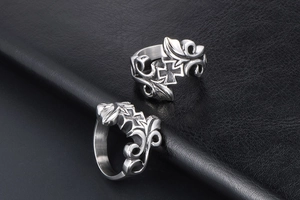 Detail of gothic stainless steel rings featuring intricate floral vine and cross carvings