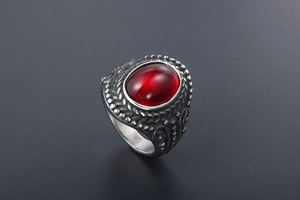 Macro detail of vintage titanium steel ring with red oval gemstone and ornate engraving