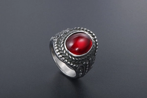 Macro shot of vintage titanium steel ring featuring an oval red gemstone and carved details