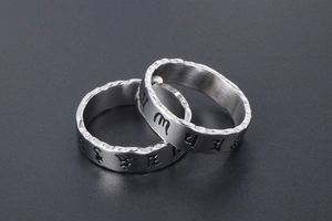 Macro detail of silver titanium rings with Sanskrit engravings and hammered textures