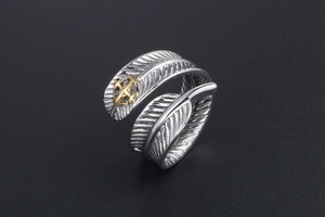 Vue macro d'une bague plume vintage avec texture argentée et détail d'ancre dorée