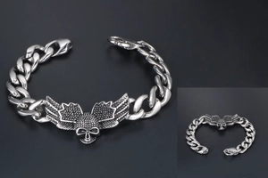 Detailed macro view of vintage stainless steel skull wing charm on a cuban chain