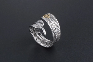 Détail d'une bague plume vintage avec texture argentée et accent d'ancre dorée