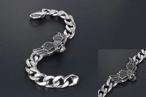 Macro detail of men's stainless steel punk curb chain bracelet with winged skull emblem