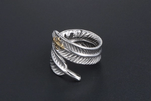 Détail macro d'une bague plume vintage en acier titane avec motif ancre dorée et fini vieilli
