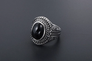 Detail of vintage stainless steel ring featuring black oval stone and ornate engraving