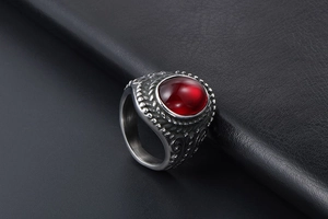 Close-up of vintage titanium steel ring with a large oval red gemstone and embossed patterns