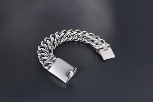 Close-up of a wide silver stainless steel curb chain bracelet with a secure metal clasp