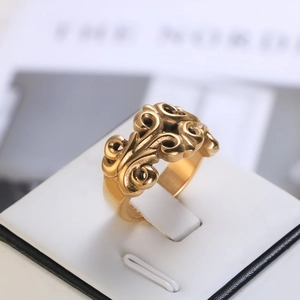 Macro shot of gold vintage carved floral pattern on a wide stainless steel ring band