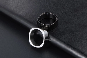 Set of matte black and polished silver square-shaped rings on black leather texture