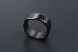 Macro view of men's square-round black steel ring with matte brushed and polished finish