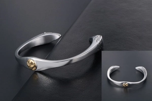 Macro detail of vintage eagle feather bangle in matte titanium steel with gold emblem