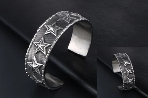 Macro view of vintage silver star bangle with relief star motifs and grid texture details