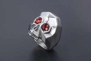Detail of silver skull ring with geometric facets and red gemstone eyes for men