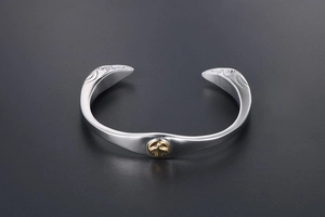 Macro detail of silver titanium steel eagle cuff bracelet with central gold bird emblem