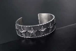 Detail of vintage punk star pattern and mesh texture on open cuff metal bracelet