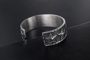 Detailed macro view of vintage stainless steel star cuff with embossed punk textures
