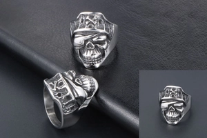 Macro shot of vintage silver stainless steel pirate skull ring on a black leather background