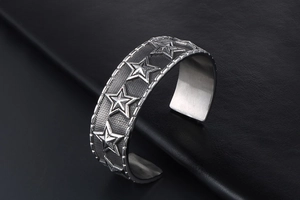 Detail of vintage silver cuff bracelet with engraved stars and textured mesh finish