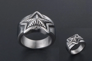 Detail of silver stainless steel star ring showing radial texture and industrial design