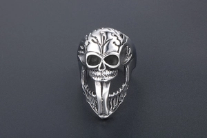 Macro detail of gothic skull ring with long fangs and engraved branch patterns in steel