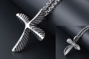 Macro detail of silver stainless steel feather cross pendant with clear leaf textures
