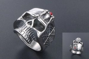 Detail of gothic skull ring with red gemstone and spider web relief on titanium steel