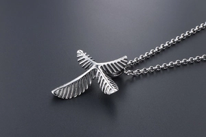 Macro detail of stainless steel eagle pendant with intricate feather texture and cross chain