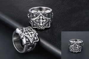 Macro shot of vintage stainless steel rings with gothic cross shield on black leather background