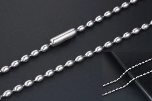 Macro detail of polished stainless steel ball chain with cylindrical connector on leather