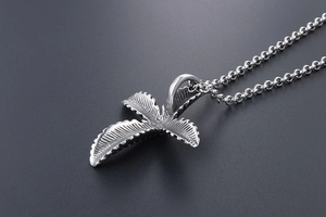 Macro view of vintage stainless steel leaf cross pendant with detailed feather textures