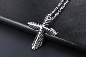 Macro view of vintage silver steel cross pendant with leaf texture on leather background