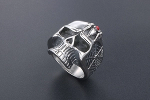 Close-up of vintage skull ring with red gemstone spider and web texture on metal surface