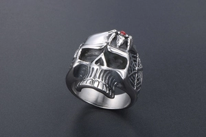 Detail of vintage skull ring featuring a red crystal spider and engraved cobweb textures