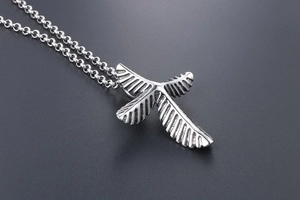 Detailed macro view of vintage silver feather and cross pendant with fine engraved texture