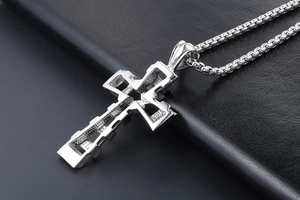Close-up of silver titanium steel cross pendant with hollow structure and box chain