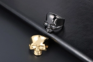 Detailed view of 3D skull rings in gold and gunmetal finish on leather background